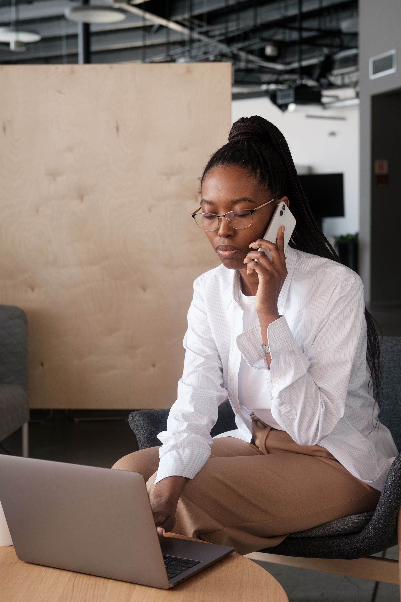 A businesswoman on a call while reading information on her laptop.