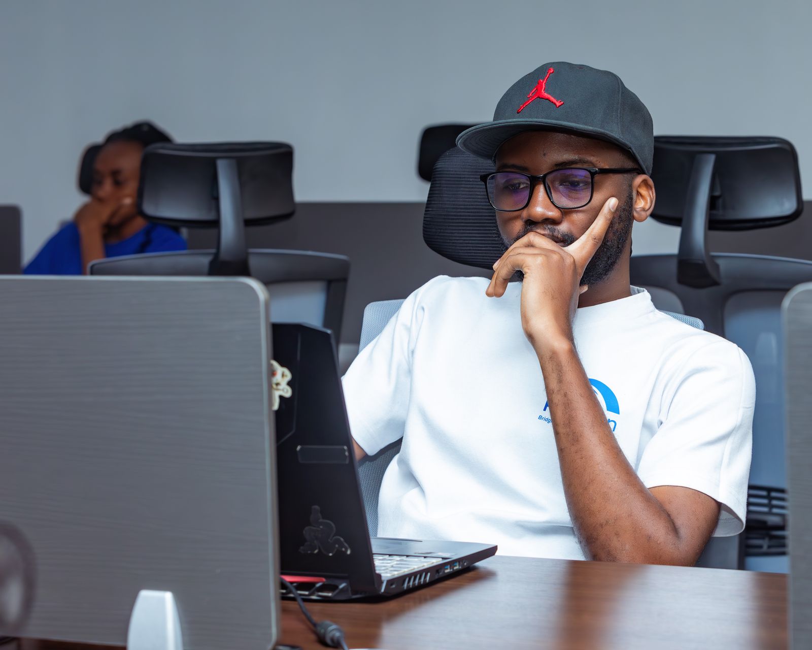 A professional thinking through a problem at his laptop in a modern office.